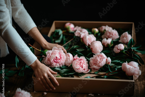 Fototapeta Naklejka Na Ścianę i Meble -  Woman takes flowers out of a packing box. generative ai
