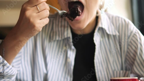 Young mixed race woman eating plant based vegan cake and enjoying each bite in restaurant. High quality lifestyle 4K healthy dessert concept footage, Thailand.