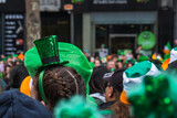 Woman with green hat in the crowd, people in the street with costumes, irish flag colours, Paddy's day parade in Dublin city, Ireland