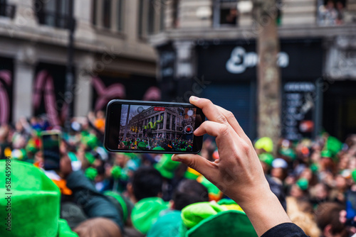 Taking a photo of the celebration, Saint Patrick's day parade in Dublin city center, hand holding a phone, blurred backgroud