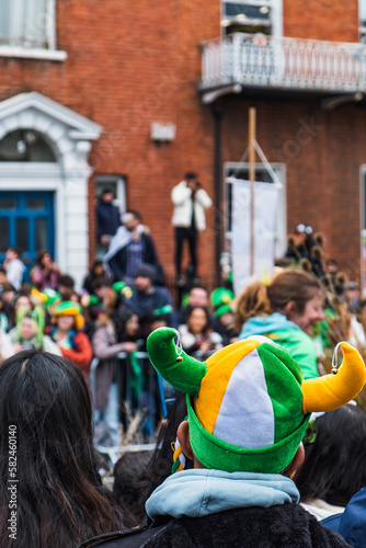 Green hat in the crowd, people in the street with costumes, irish flag colours, Paddy's day parade in Dublin city, Ireland
