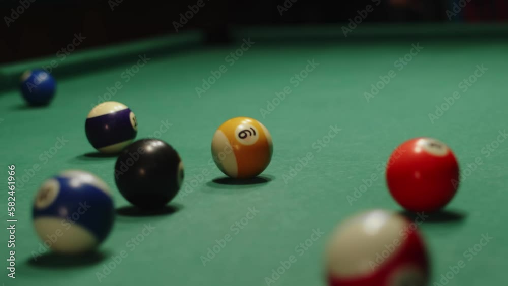 Closeup billiard balls on table, man hits cue and breaks pyramid of balls, front view. Mans hand hits billiard ball with cue. Concept sports and recreation Closeup billiard balls on table, man hits cue and breaks pyramid of balls, front view. Mans hand hits billiard ball with cue. Concept sports and recreation