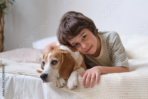 Happy boy embracing rescued beagle on bed, both smiling. adopt a loving pet and create lifelong memories together.