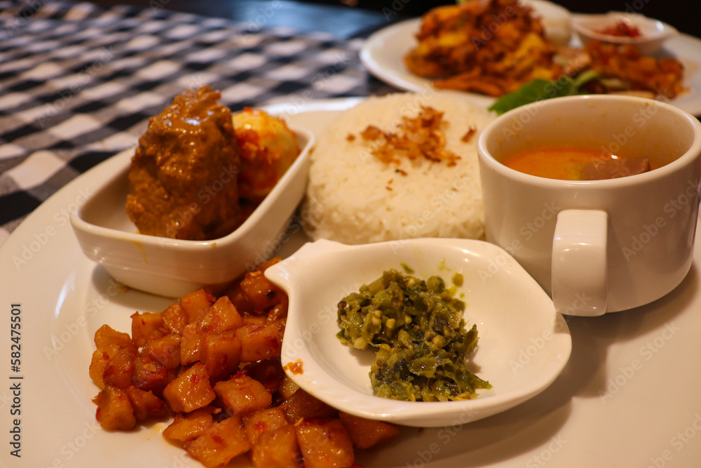 A Complete Dish of Padangnese Food with Rendang, Spicy Potato, Rice, Green Chilies, and Vegetable Curry Soup from Indonesia A Complete Dish of Padangnese Food with Rendang, Spicy Potato, Rice, Green Chilies, and Vegetable Curry Soup from Indonesia