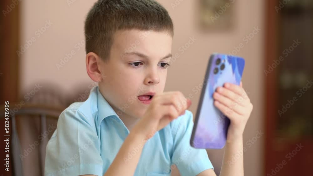 Boy typing text message by smartphone at home. A schoolboy holds a modern phone in his hands and communicates in a school chat or social networks. Boy typing text message by smartphone at home. A schoolboy holds a modern phone in his hands and communicates in a school chat or social networks.