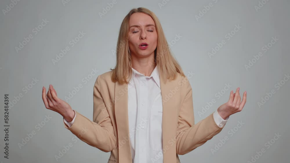 Keep calm down, relax, inner balance. Business woman breathes deeply with mudra gesture, eyes closed, meditating with concentrated thoughts, peaceful mind. Female girl in suit on gray background Keep calm down, relax, inner balance. Business woman breathes deeply with mudra gesture, eyes closed, meditating with concentrated thoughts, peaceful mind. Female girl in suit on gray background