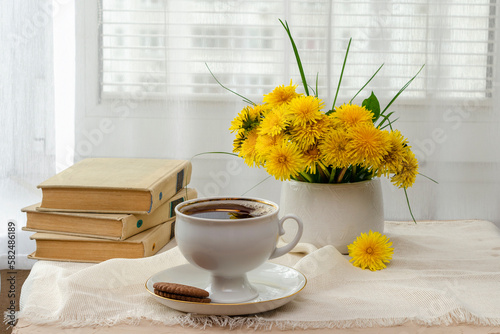 still life, bouquet of yellow wild flowers, tea with sweets, a book on the windowsill near the window and tea on the windowsill, tea party on vacation in summer