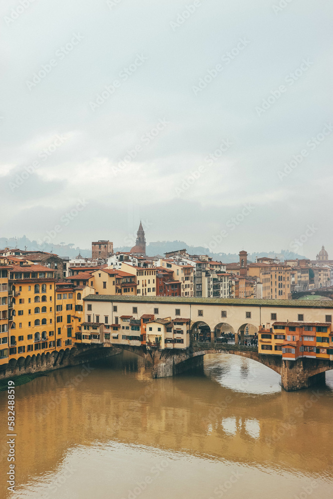 Colorful buildings by the river in italian town and medieval famous bridge from up the window