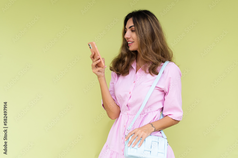 Young woman in casual wear isolated on green background looking at phone screen with big smile reading message Young woman in casual wear isolated on green background looking at phone screen with big smile reading message