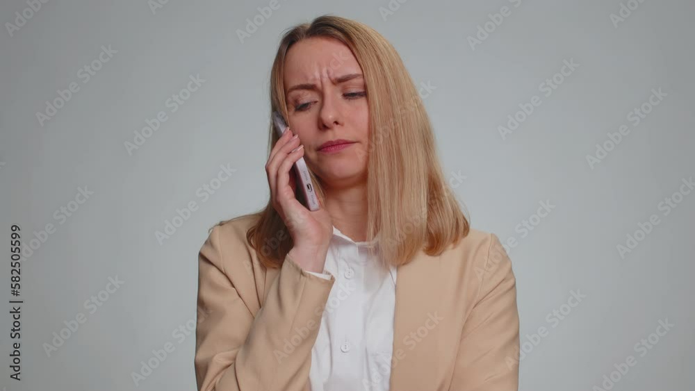 Portrait of disinterested young businesswoman having annoyed boring talk on smartphone. Tired sleepy freelancer woman talking on mobile phone with friend, making online conversation on gray background Portrait of disinterested young businesswoman having annoyed boring talk on smartphone. Tired sleepy freelancer woman talking on mobile phone with friend, making online conversation on gray background