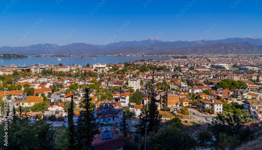 a view of a town by the water with mountains in the distance