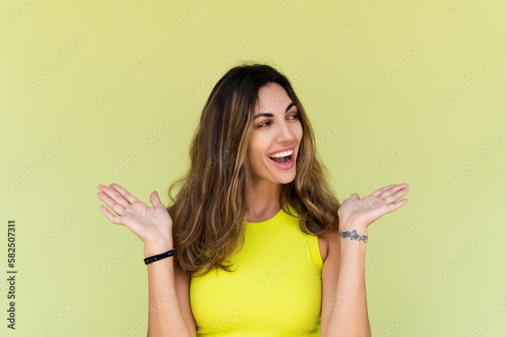 Young brunette in casual wear isolated on green background happy look aside shocked amazed surprised open mouth Young brunette in casual wear isolated on green background happy look aside shocked amazed surprised open mouth