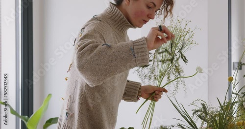 female doing new bouquet. Girl working in flower shop studio. Female florist artist cleans flowers for a beautiful bouquet, workplace view. High quality 4k footage