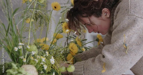 female doing new bouquet. Girl working in flower shop studio. Female florist artist cleans flowers for a beautiful bouquet, workplace view. High quality 4k footage