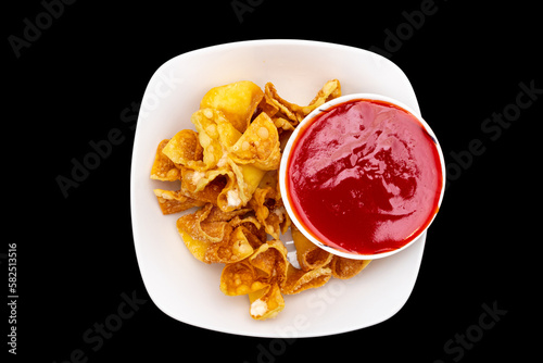 Overhead view of crab rangoons with sweet and sour dipping sauce on a black background photo