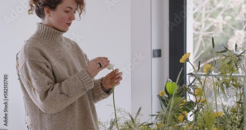 female doing new bouquet. Girl working in flower shop studio. Female florist artist cleans flowers for a beautiful bouquet, workplace view. High quality 4k footage