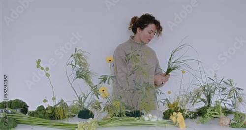 female doing new bouquet. Florist makes a floral oasis. Girl working in flower shop studio. Female florist artist cleans flowers for a beautiful bouquet, workplace view. High quality 4k footage