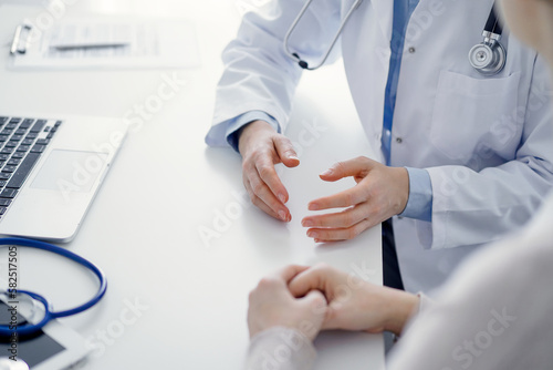 Doctor and patient discussing current health questions while sitting at the table in clinic office, only hands closeup. Medicine concept