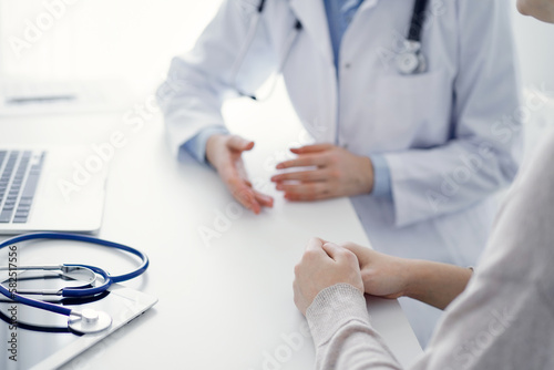 Doctor and patient discussing current health questions while sitting at the table in clinic office, only hands closeup. Medicine concept