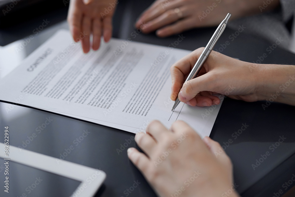 Business people signing contract papers while sitting at the glass table in office, closeup. Partners or lawyers working together at meeting. Teamwork, partnership, success concept Business people signing contract papers while sitting at the glass table in office, closeup. Partners or lawyers working together at meeting. Teamwork, partnership, success concept
