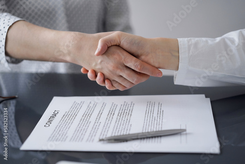 Business people signing contract papers while sitting at the glass table in office, closeup. Partners or lawyers working together at meeting. Teamwork, partnership, success concept