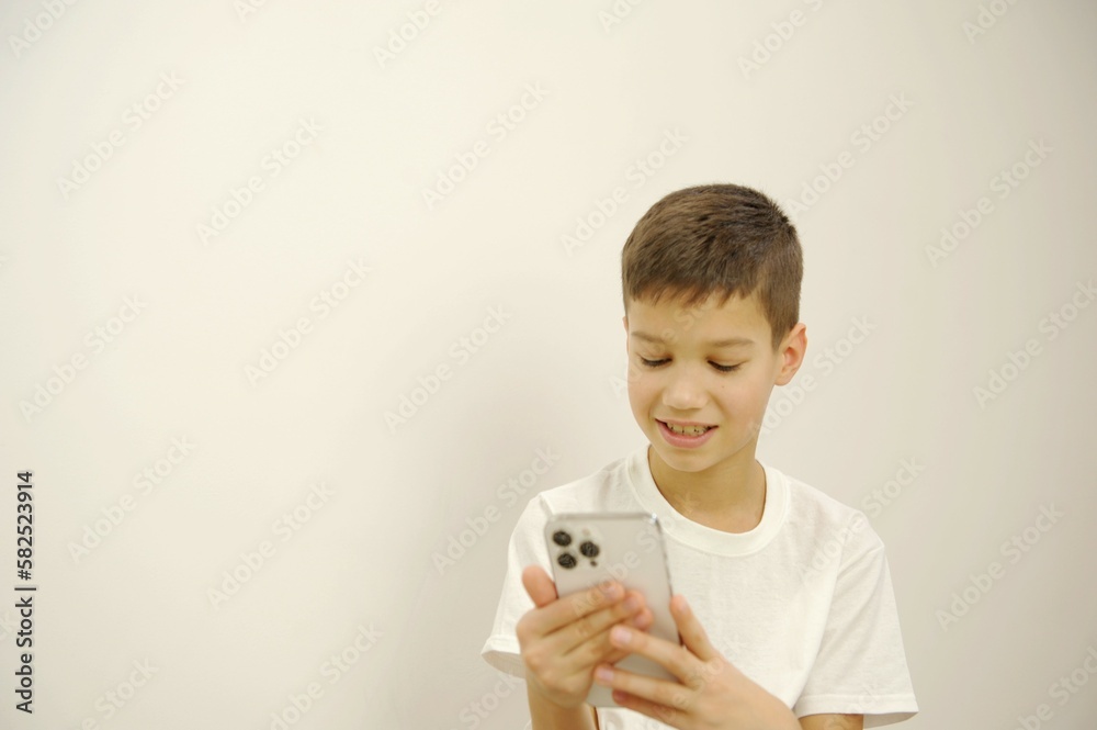 Using smartphone, looks calm. Caucasian boy portrait isolated on white studio background. Beautiful teen male model in white shirt posing. Concept of human emotions, facial expression, sales, ad Using smartphone, looks calm. Caucasian boy portrait isolated on white studio background. Beautiful teen male model in white shirt posing. Concept of human emotions, facial expression, sales, ad