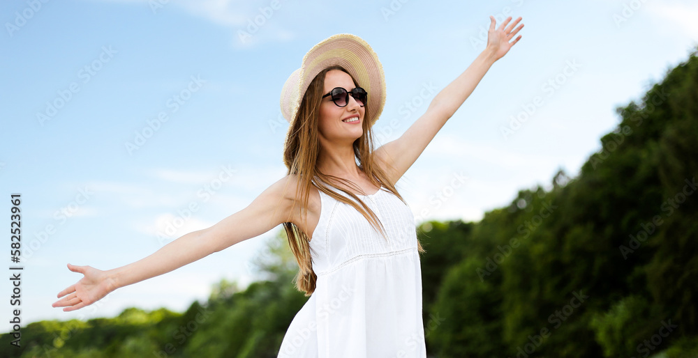 Happy smiling woman in free happiness bliss on ocean beach standing with a hat, sunglasses, and open hands. Portrait of a multicultural female model in white summer dress enjoying nature Happy smiling woman in free happiness bliss on ocean beach standing with a hat, sunglasses, and open hands. Portrait of a multicultural female model in white summer dress enjoying nature