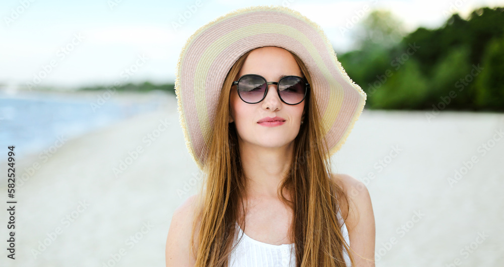 Portrait of a happy smiling woman in free happiness bliss on ocean beach standing with a hat and sunglasses. A female model in a white summer dress enjoying nature during travel holidays vacation Portrait of a happy smiling woman in free happiness bliss on ocean beach standing with a hat and sunglasses. A female model in a white summer dress enjoying nature during travel holidays vacation