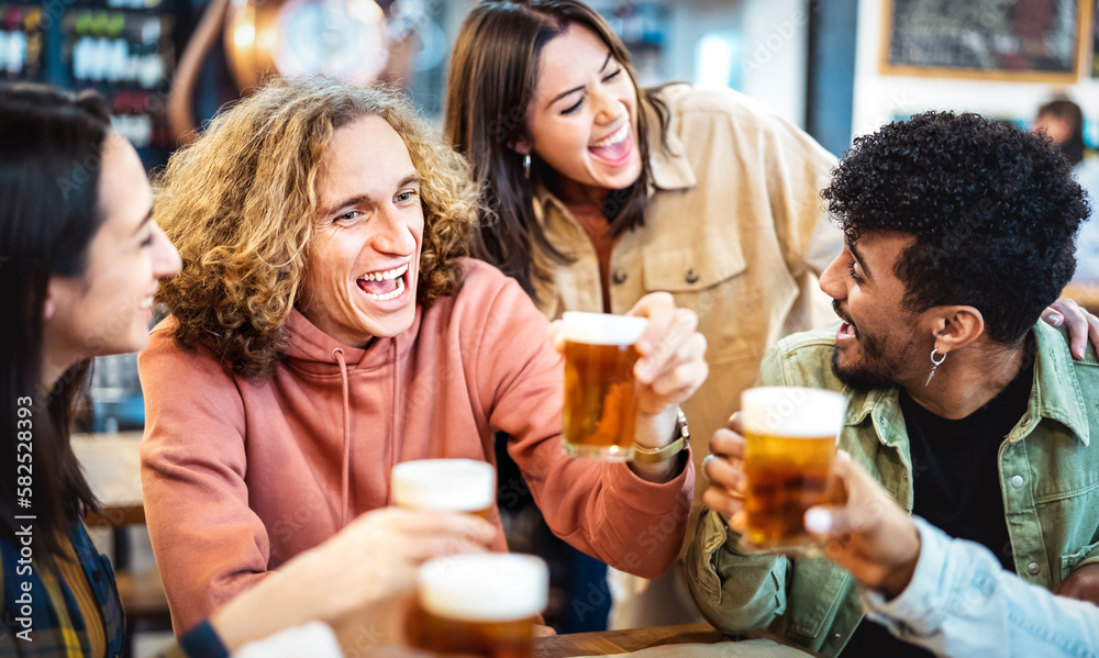 Multi racial hipster friends drinking and toasting beer at brewery bar restaurant - Food and beverage life style concept with men and women having dinner together - Warm filter with focus on left guy Multi racial hipster friends drinking and toasting beer at brewery bar restaurant - Food and beverage life style concept with men and women having dinner together - Warm filter with focus on left guy