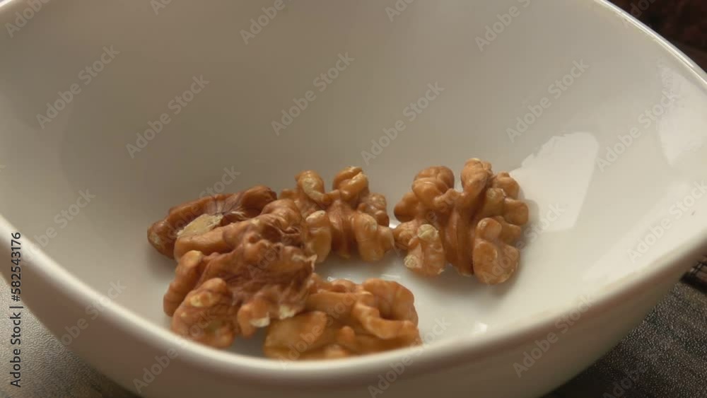 Walnut being poured into a white plate Walnut being poured into a white plate
