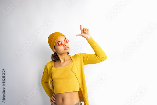 Teen girl african american woman wearing yellow sweater with an idea or question pointing finger up on white background.