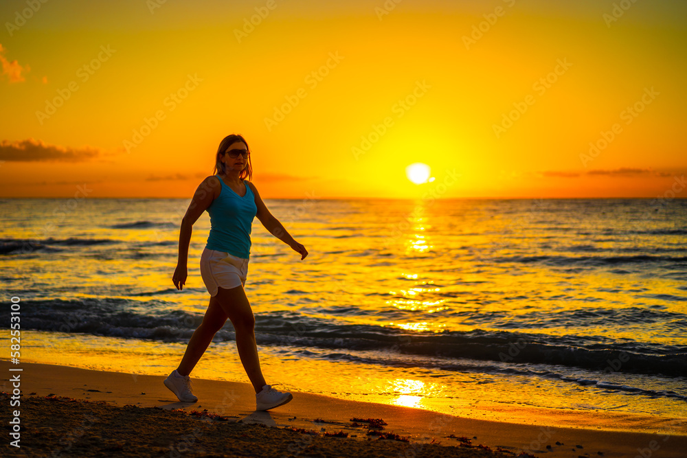 Beach holiday - beautiful woman walking, running on sunny, tropical beach in the morning
