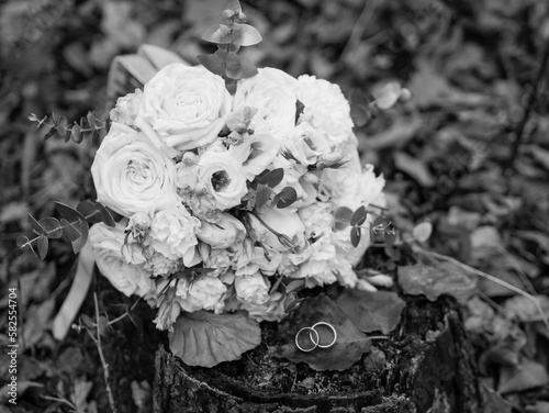 Wedding bouquet of white flowers and rings on monochrome leaves. Wedding details 