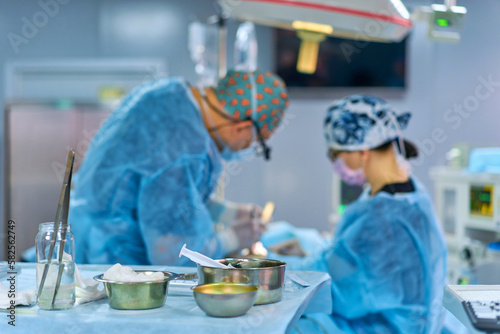 surgeon in the operating room is standing at the table with the patient under the lamp