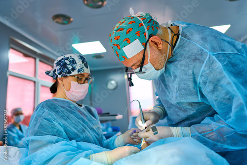 surgeon in the operating room is standing at the table with the patient under the lamp