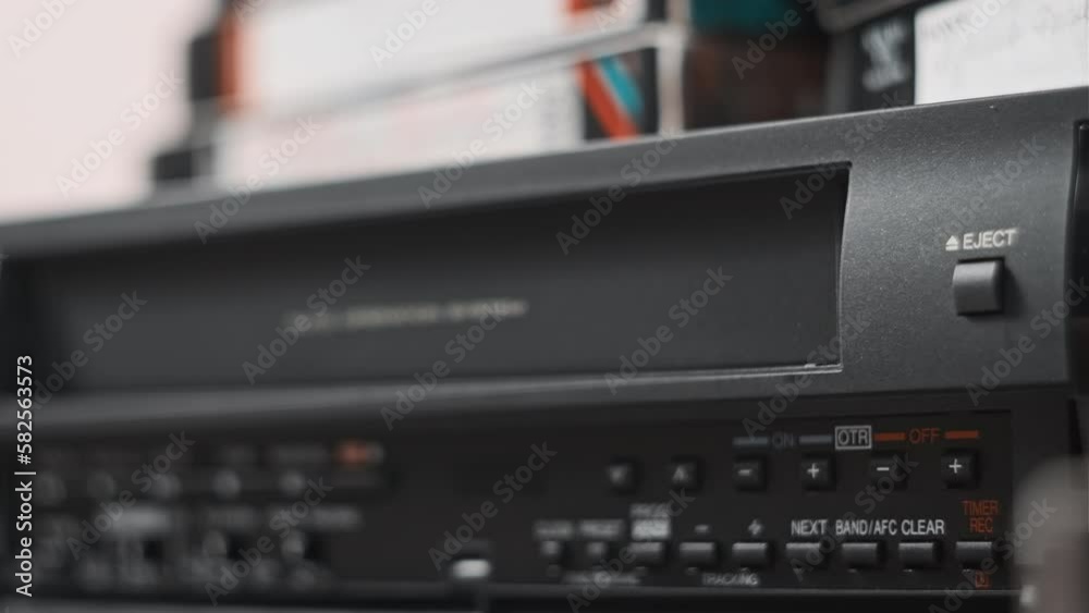 Eject VHS tape cassette from VCR player. Male hand pulls out VHS from a