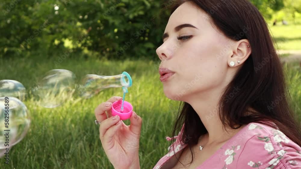 Woman sitting on white bedsheet, blowing soap bubbles, smiling. Lady have a rest in the city park, green grass lawn. Travel, vacation, picnic set
Woman sitting on white bedsheet, blowing soap bubbles, smiling. Lady have a rest in the city park, green grass lawn. Travel, vacation, picnic set