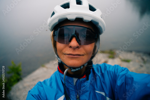 cyclist takes a selfie in a helmet and sunglasses in foggy day © IBRESTER