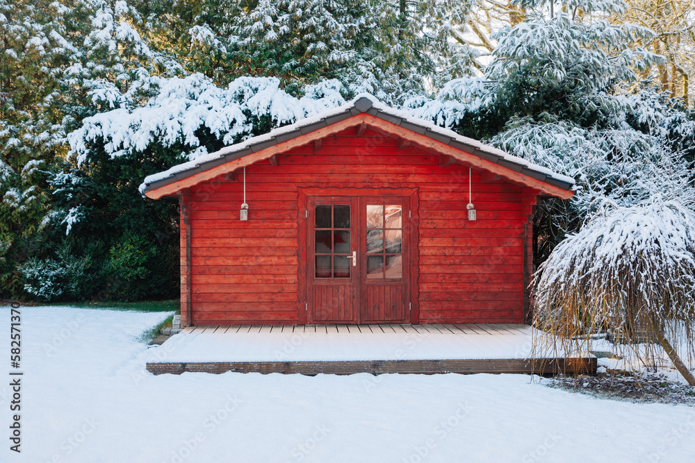 Red wooden house in the garden, in winter.