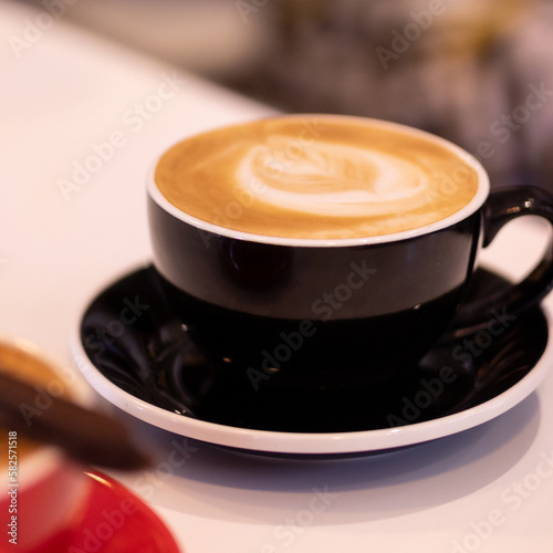 Latte made by bartender with leaf drawing in black mug