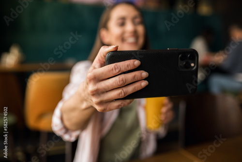 Close up a woman holding a phone and taking a selfie in a restaurant