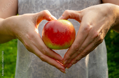 woman's hands hold red delicious apple, making heart shape on apple. Healthy lifestyle concept photo