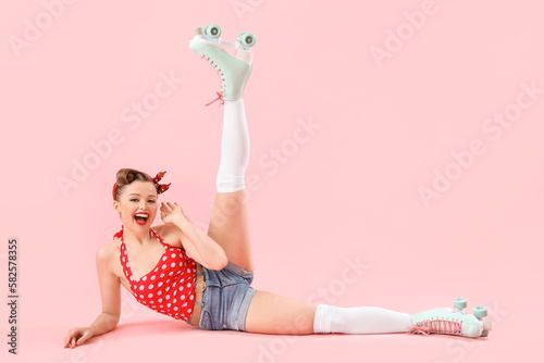 Fototapeta Naklejka Na Ścianę i Meble -  Young pin-up woman in roller skates on pink background