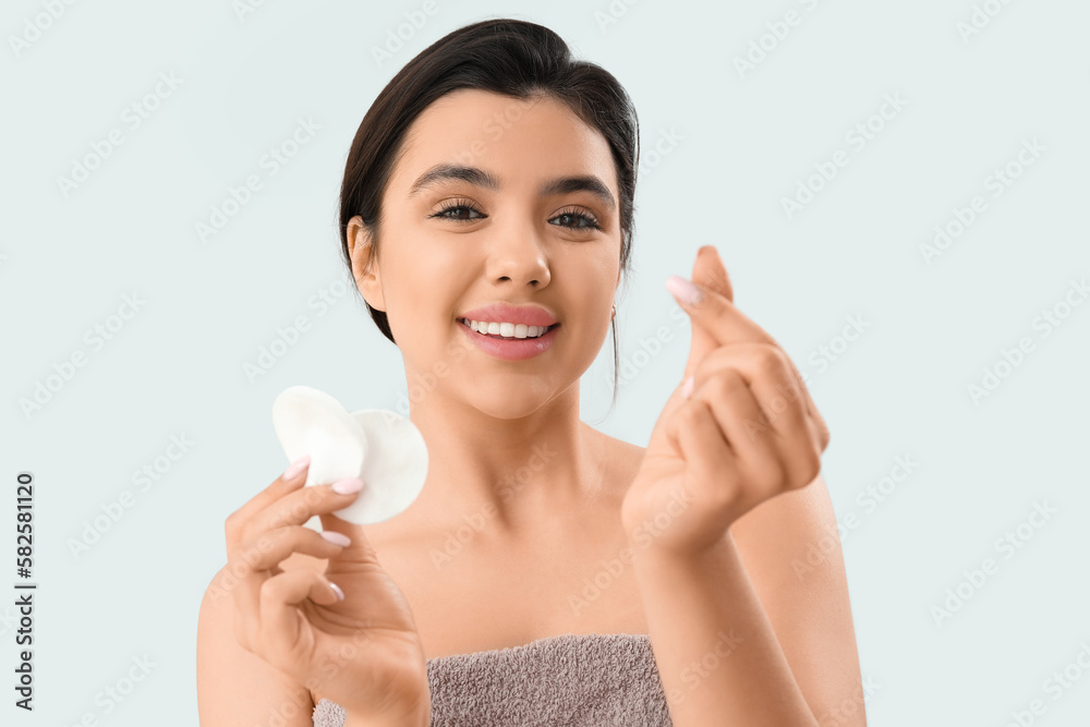 Young woman with cotton pads making heart on light background, closeup Young woman with cotton pads making heart on light background, closeup