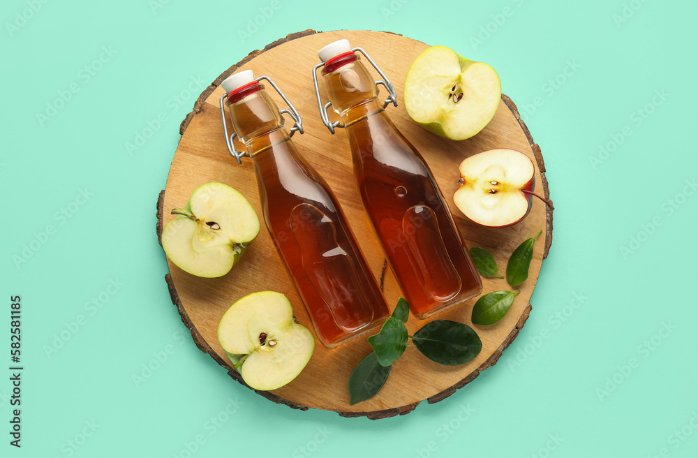 Board with glass bottles of fresh apple cider vinegar and fruits on