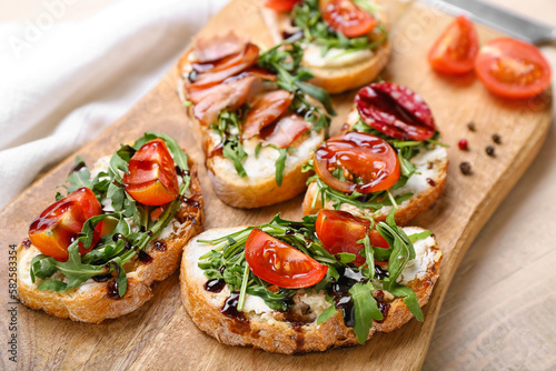 Wooden board of tasty sandwiches with cream cheese, arugula and tomatoes, closeup
