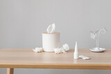Nasal drops with pills and tissue box on table near grey wall. Allergy concept