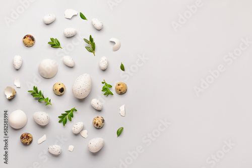 Creative composition with Easter eggs and plant leaves on grey background