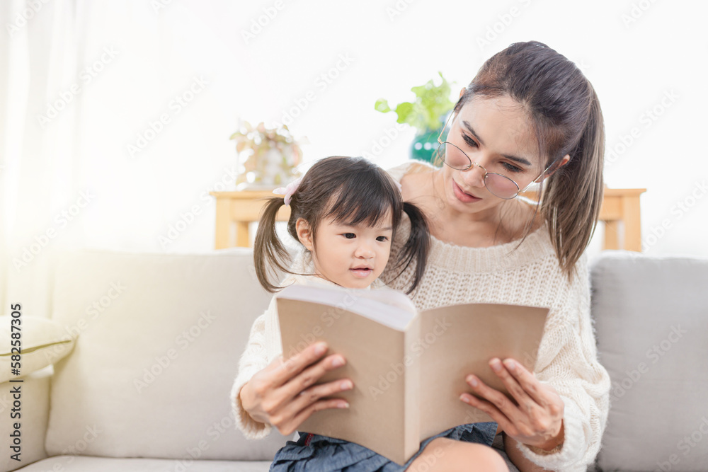 Light and blur people, Asian children and her mother reading a book, they sitting on sofa, happiness in family time, child learning and development Light and blur people, Asian children and her mother reading a book, they sitting on sofa, happiness in family time, child learning and development