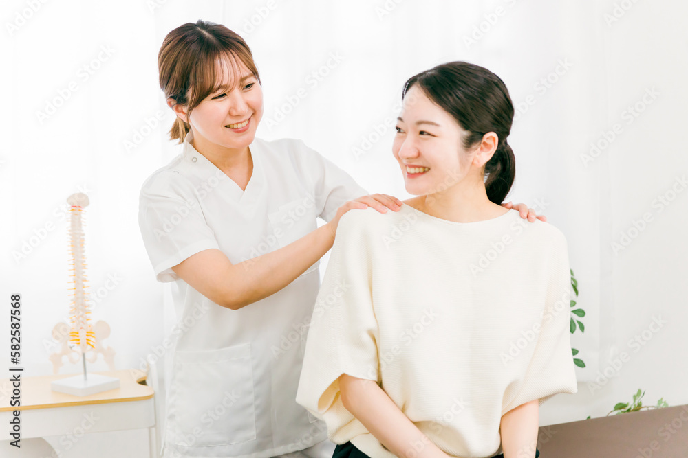 Fototapeta premium 整骨院・接骨院で診察・相談・カウンセリングする整体師・・マッサージ師・セラピストの女性（腰痛） 